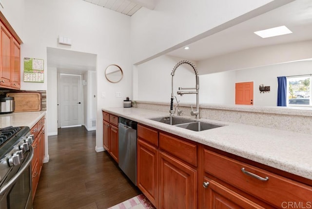 kitchen featuring a skylight, dark wood-style flooring, stainless steel appliances, light countertops, and a sink