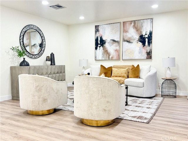 living room with baseboards, wood finished floors, visible vents, and recessed lighting