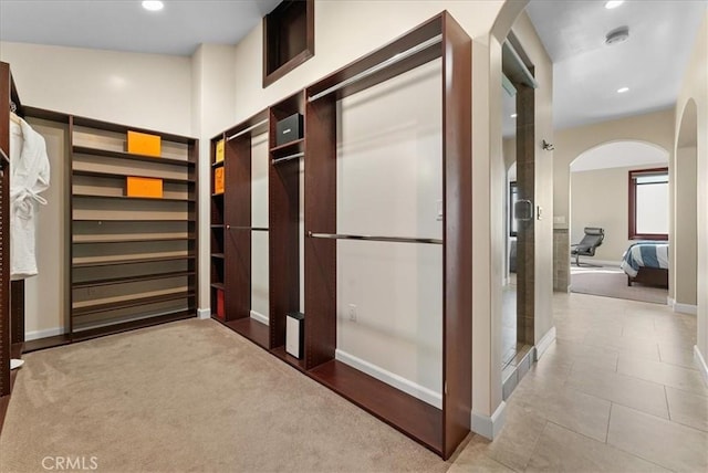 walk in closet featuring arched walkways and light tile patterned flooring