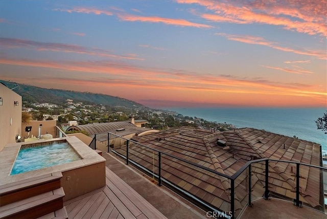 balcony with a hot tub and a water and mountain view