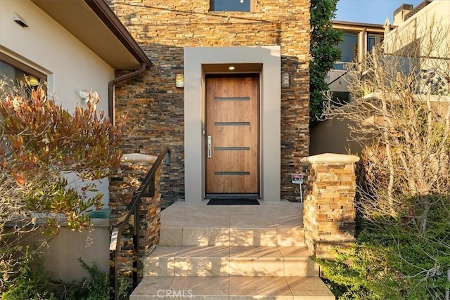 entrance to property with stone siding, brick siding, and stucco siding