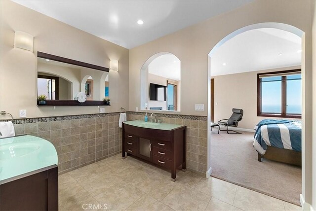 31422 Ceanothus Dr, Laguna Beach, CA 92651 - ensuite bathroom featuring tile walls, two vanities, tile patterned floors, wainscoting, and recessed lighting