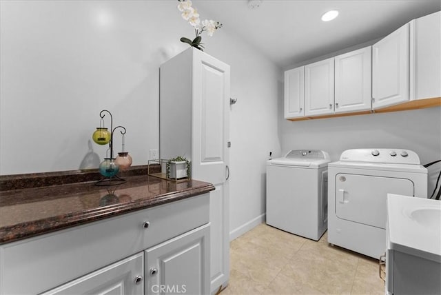 laundry area with cabinet space, baseboards, washer and clothes dryer, a sink, and light tile patterned flooring