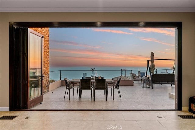 interior space featuring a water view, light tile patterned floors, visible vents, and ornamental molding