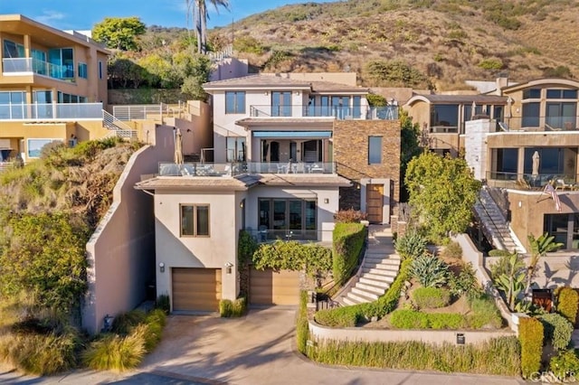 view of front of property featuring concrete driveway, an attached garage, a residential view, and stucco siding