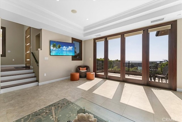 unfurnished living room with baseboards, a tray ceiling, visible vents, and crown molding