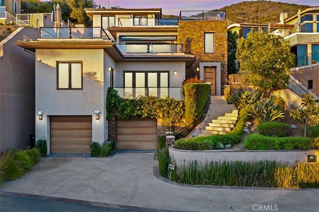 view of front of home featuring a balcony, a garage, concrete driveway, stairway, and stucco siding