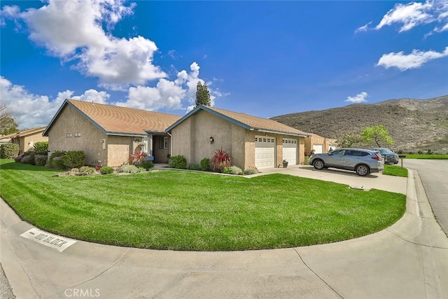 view of front facade featuring driveway, a garage, stucco siding, a mountain view, and a front yard