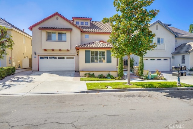 mediterranean / spanish house with an attached garage, a tile roof, concrete driveway, and stucco siding