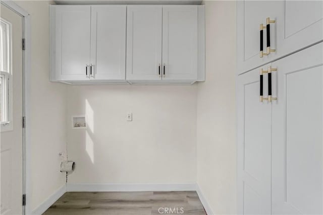 laundry area with cabinet space, hookup for a washing machine, baseboards, and light wood-style floors