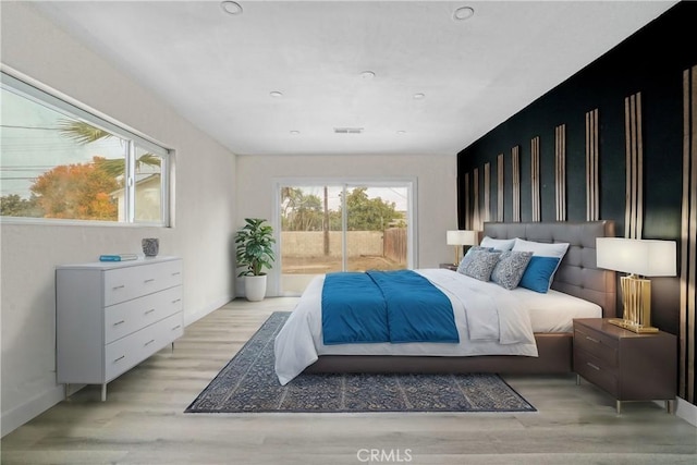 bedroom featuring access to exterior, multiple windows, light wood-style floors, and baseboards