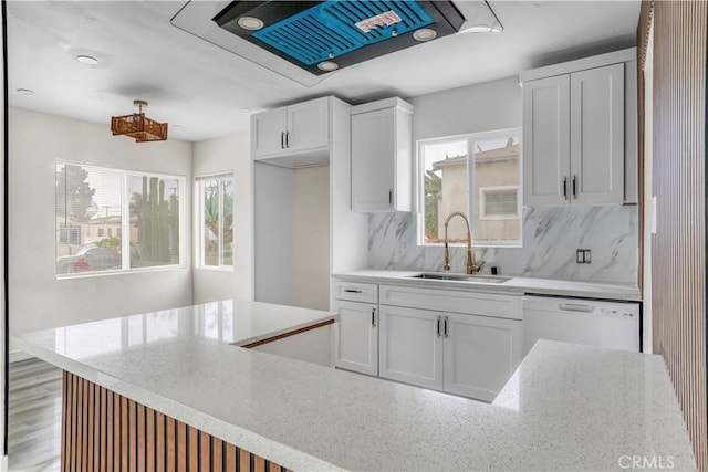 kitchen featuring light stone counters, white dishwasher, a sink, white cabinets, and tasteful backsplash