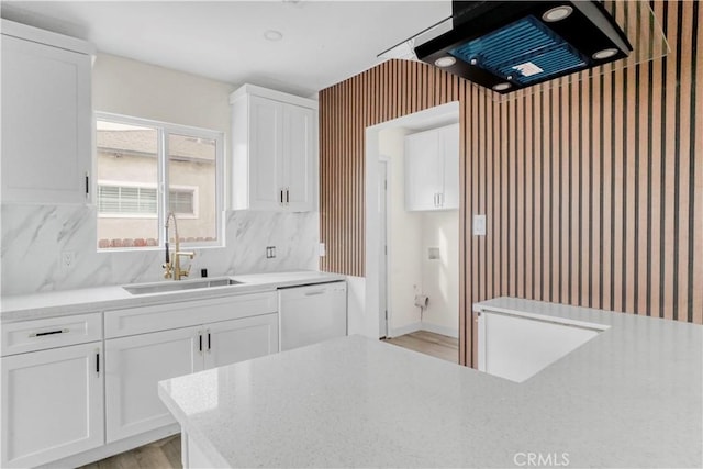 kitchen featuring dishwasher, light countertops, a sink, and white cabinetry