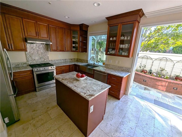 kitchen with stainless steel appliances, a kitchen island, glass insert cabinets, and under cabinet range hood