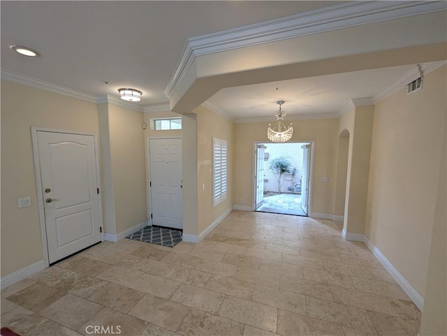 entryway with ornamental molding, arched walkways, visible vents, and baseboards