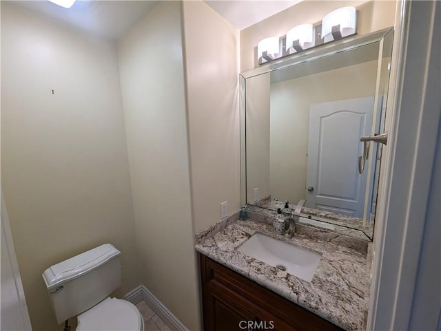 bathroom with toilet, vanity, and baseboards