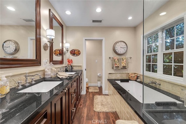 full bath featuring a garden tub, toilet, a sink, and visible vents