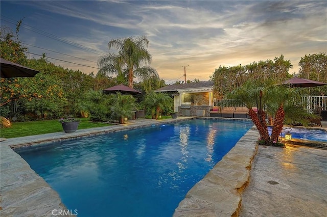 pool at dusk featuring fence and area for grilling