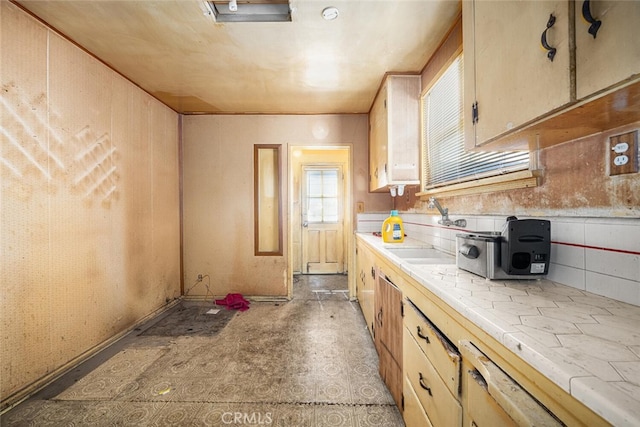 kitchen featuring tile countertops, backsplash, a sink, and light brown cabinets