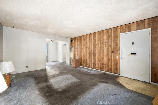 spare room featuring wooden walls and a textured ceiling