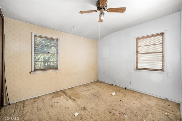 empty room with a ceiling fan, lofted ceiling, carpet flooring, and wallpapered walls