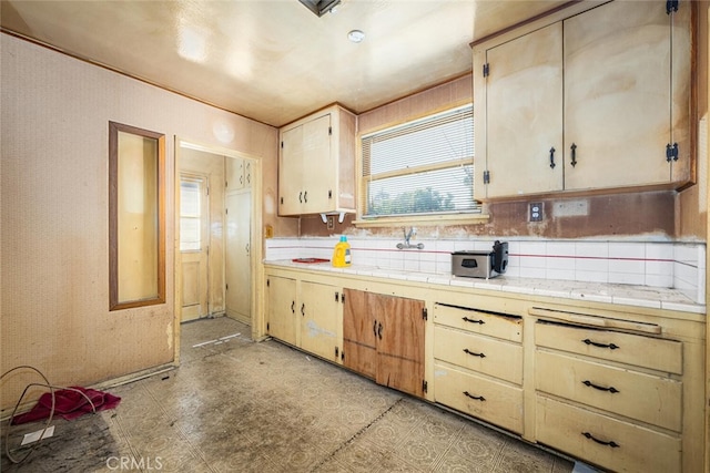 kitchen with tasteful backsplash, a sink, tile countertops, and light floors