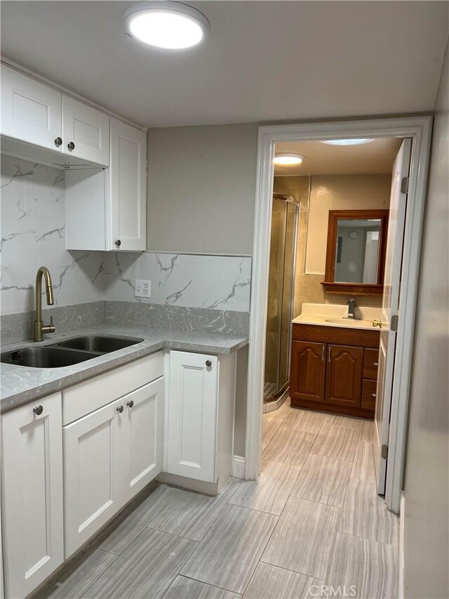 kitchen with light countertops, decorative backsplash, a sink, and white cabinets