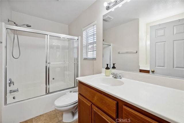 full bathroom featuring shower / bath combination with glass door, tile patterned flooring, vanity, and toilet