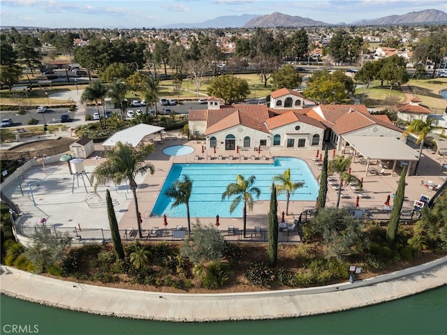 community pool featuring a water and mountain view and a patio