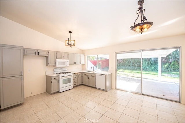 kitchen featuring lofted ceiling, gray cabinets, light countertops, a sink, and white appliances