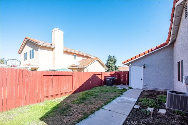 view of yard with a fenced backyard and central AC unit