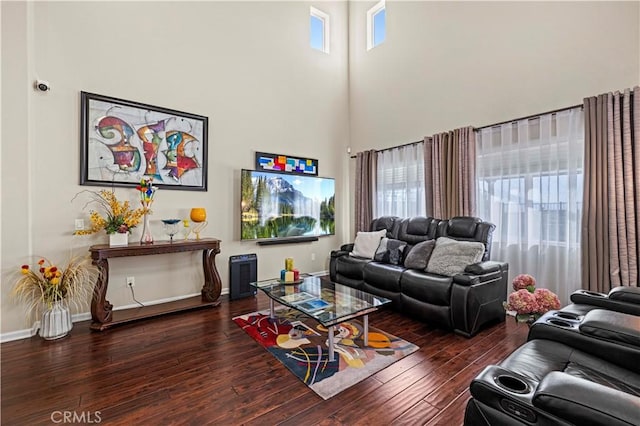 living area featuring dark wood-style flooring, a high ceiling, and baseboards