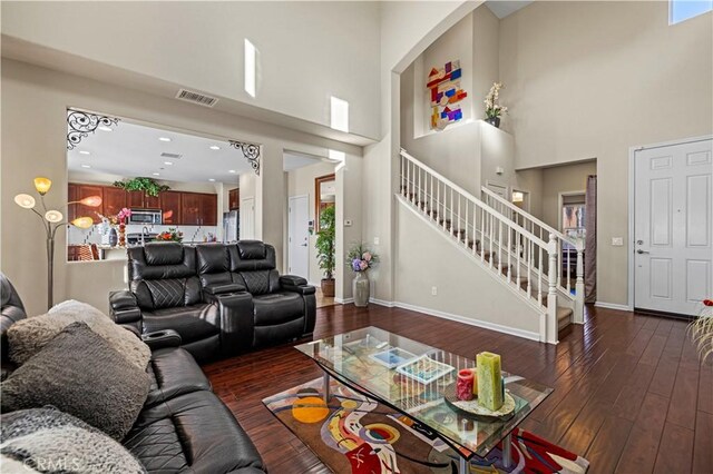 living room with dark wood-style floors, visible vents, stairway, and baseboards