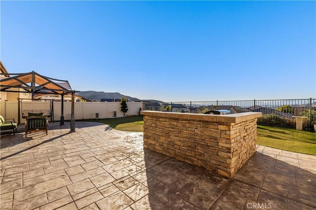 view of patio featuring a gazebo, exterior bar, a fenced backyard, and a mountain view