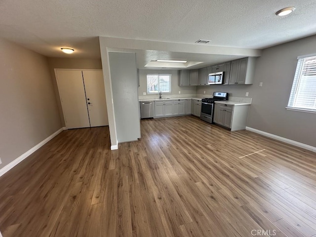 kitchen featuring gray cabinets, light countertops, visible vents, appliances with stainless steel finishes, and a sink