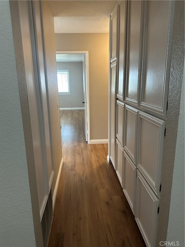 hallway featuring dark wood-type flooring, visible vents, and baseboards