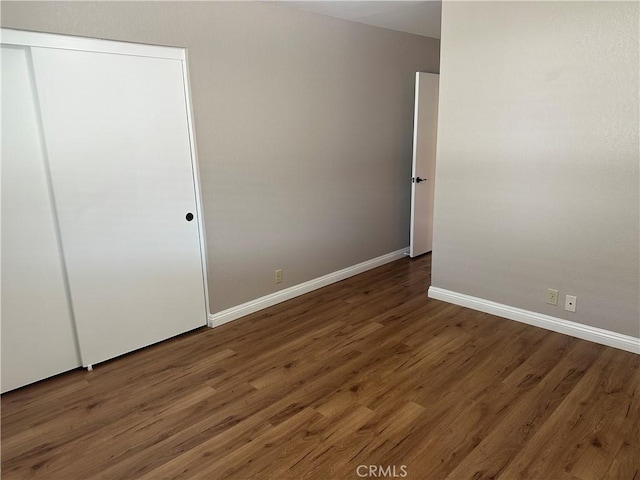 unfurnished bedroom with a closet, baseboards, and wood finished floors