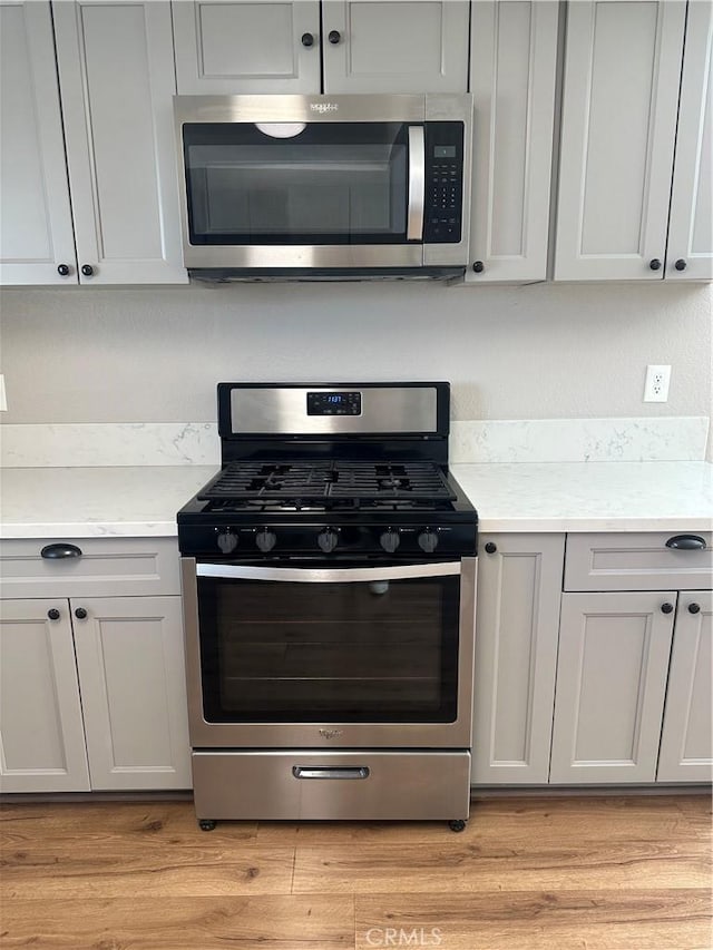 kitchen featuring light wood-style floors, stainless steel appliances, and light countertops