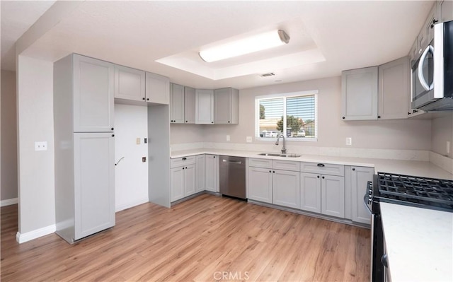 17875 Idyllwild Ln, Victorville, CA 92395 - kitchen with stainless steel appliances, a sink, a raised ceiling, light wood-style floors, and gray cabinets