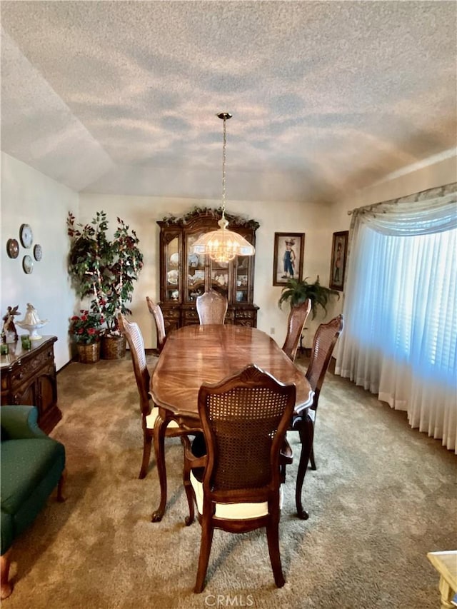 carpeted dining space featuring a textured ceiling and an inviting chandelier