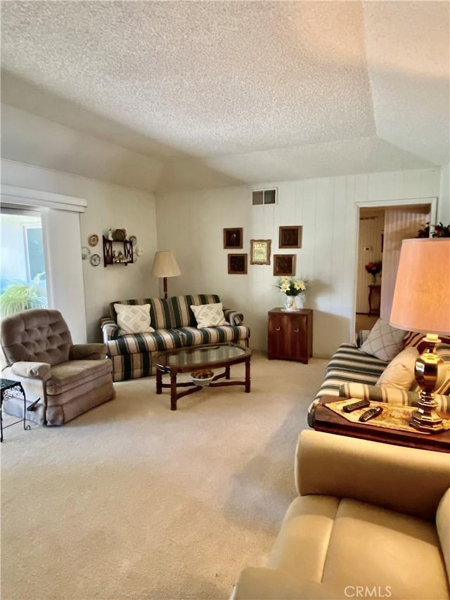 living room featuring carpet, visible vents, vaulted ceiling, and a textured ceiling