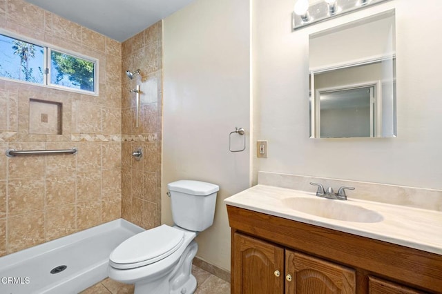 bathroom featuring toilet, tile patterned flooring, a tile shower, and vanity