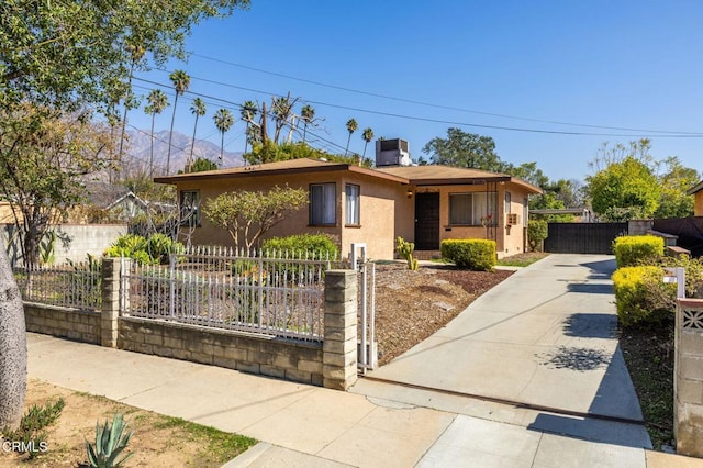 ranch-style house with a fenced front yard, a gate, and stucco siding