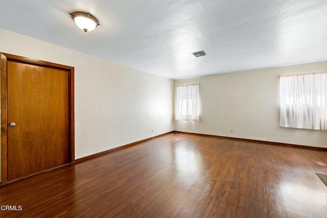 unfurnished room featuring wood finished floors, visible vents, and baseboards