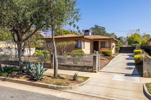 ranch-style house featuring a fenced front yard, concrete driveway, and stucco siding