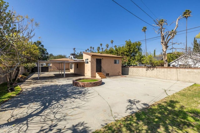 rear view of house featuring a fenced backyard, driveway, a patio, and stucco siding