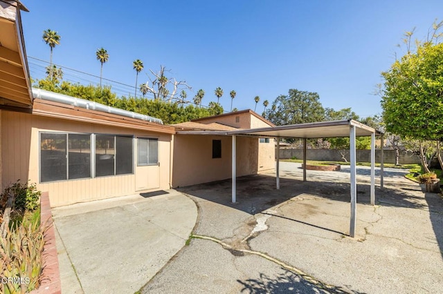 exterior space featuring aphalt driveway, fence, and an attached carport