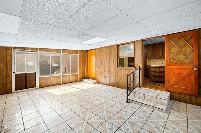 empty room with a paneled ceiling and wood walls