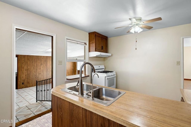 kitchen featuring ceiling fan, gas range gas stove, light countertops, under cabinet range hood, and a sink