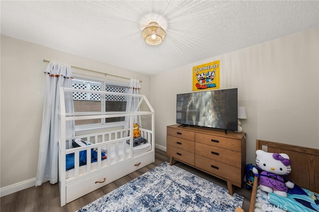 bedroom featuring a textured ceiling, dark wood-type flooring, and baseboards